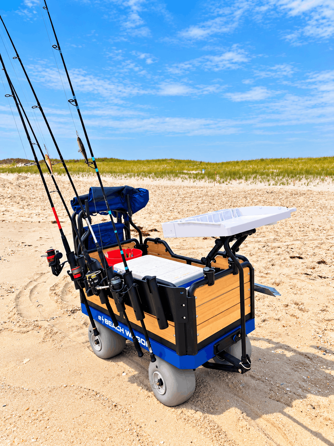 A motorized beach trolley on the beach outfitted with fishing accessories: fillet board, 6-fishing rod rack, and sand spike holders