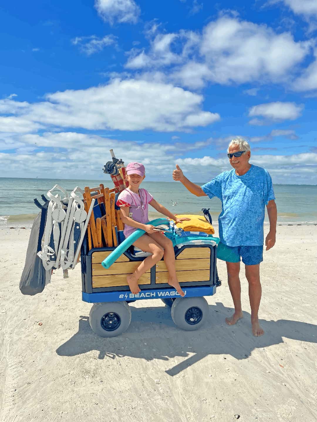 Customer with an e-Beach Wagon filled with beach gear on a sandy beach.